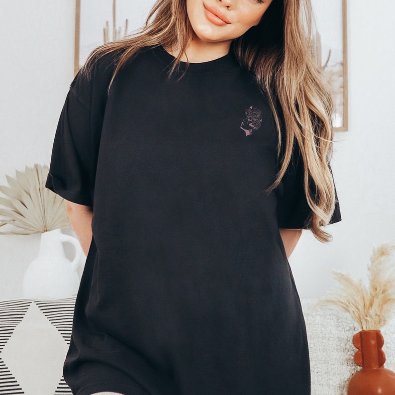 May include: A black oversized t-shirt with a small floral design on the left chest.