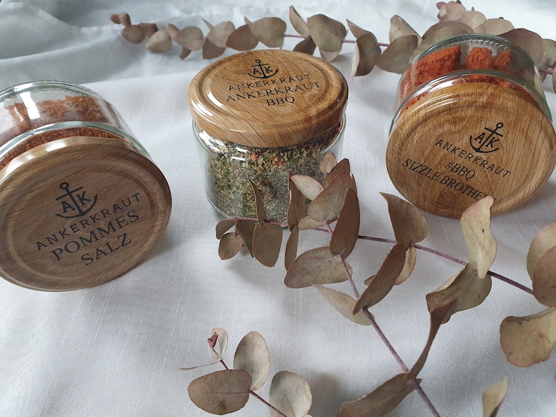 May include: Three glass jars with wooden lids and labels. The labels read "Ankerkraut Pommes Salz", "Ankerkraut BBQ", and "Ankerkraut BBQ Sizzle Brother".