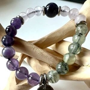 Puede incluir: Un brazalete de piedras preciosas multicolores con un dije de plata. El brazalete presenta cuentas de amatista, cuarzo rosa, aventurina verde y ónix negro.