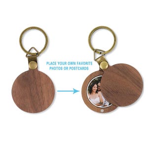 May include: A round wooden keychain with a hinged cover, revealing a photo. The keychain has a brass-colored ring and a leather strap. The text "PLACE YOUR OWN FAVORITE PHOTOS OR POSTCARDS" is visible.