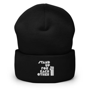 May include: Black beanie with a white embroidered message that reads "Stand Up For Each Other" and a raised fist.