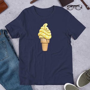 Könnte beinhalten: Ein marineblaues T-Shirt mit einer gelben und weißen Schlange, die sich um eine gelbe und weiße Eistüte windet.