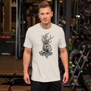 Puede incluir: Una camiseta blanca con una ilustración en blanco y negro de un conejo con pajarita y cuernos.