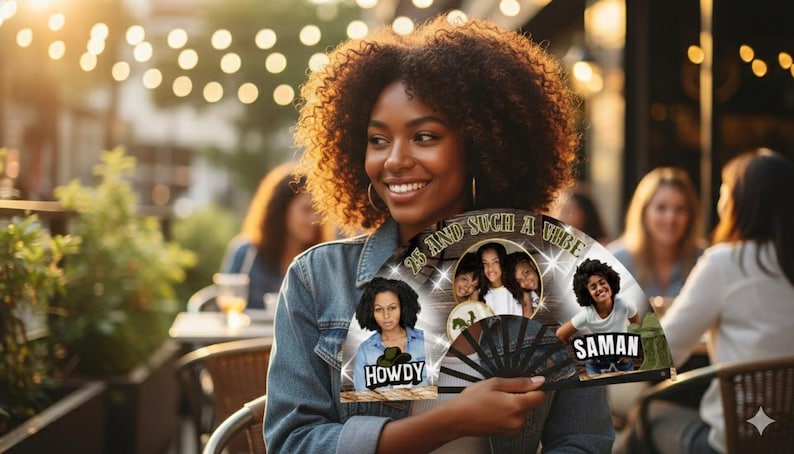 May include: A woman smiles while holding a black and white fan with photos and text. The fan has the words "25 and such a vibe" and the names "Howdy" and "Saman". The background is a blurred outdoor setting with string lights.