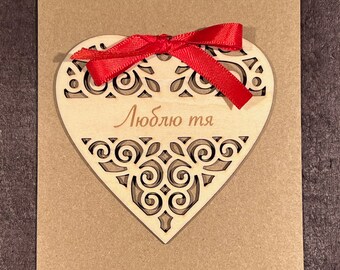 May include: A wooden heart-shaped card with a red ribbon and the text "Люблю тя" in Cyrillic script.