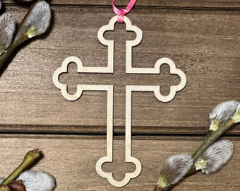 May include: A wooden cross with a delicate, ornate design, hanging from a pink ribbon. The cross is surrounded by sprigs of pussy willow branches with fuzzy gray buds.