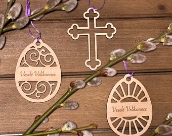May include: Three wooden Easter decorations: a cross, an egg with a swirl design, and an egg with a sunburst design. Each decoration has the text "Veselé Velikonoce" which translates to "Happy Easter" in English.