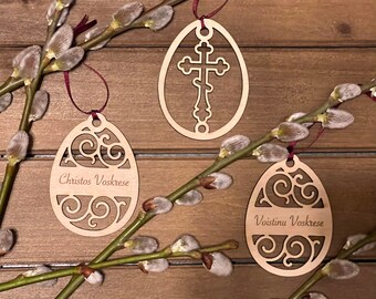 May include: Three wooden Easter egg ornaments with intricate designs. One features a cross, another says "Christos Voskrese", and the third says "Voistinu Voskrese".