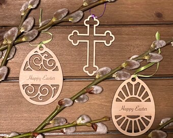 May include: Three wooden Easter decorations: a cross, an egg with a swirl design, and an egg with a sunburst design. Each decoration has the text "Happy Easter" engraved on it.