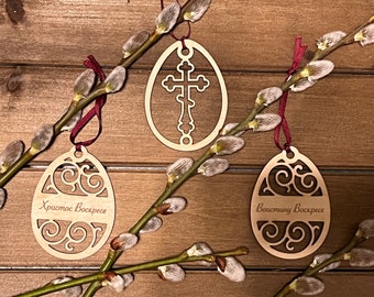 May include: Three wooden Easter egg ornaments with intricate designs. One features a cross, another has a swirling pattern, and the third has a swirling pattern with the text "Христос Воскресе" (Christ is Risen).