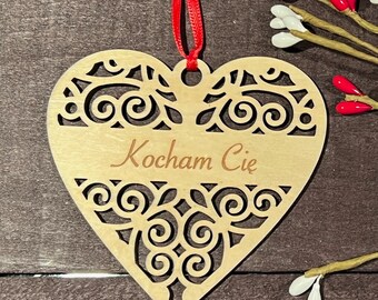 May include: A wooden heart-shaped ornament with a decorative cut-out design and the text "Kochmam Cie" in cursive.