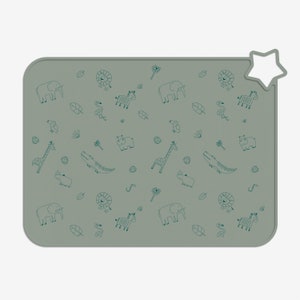 May include: A green silicone placemat featuring a repeating pattern of animals and plants. The animals include a giraffe, zebra, elephant, lion, hippopotamus, rhinoceros, and crocodile. The plants include palm trees and leaves.