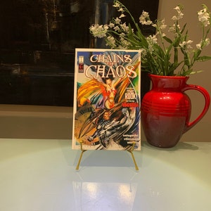 May include: A comic book titled "Chains of Chaos" featuring a clock face and a character in a red and yellow costume. The text "The Rook and starring Vampirella" is also visible.