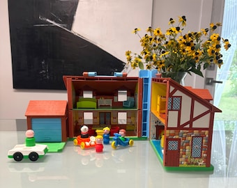 May include: A multi-level plastic dollhouse playset featuring a garage, a main house structure with open rooms, and a side section with stone-patterned walls. Includes several small plastic figures, a white car, and a yellow tricycle toy.