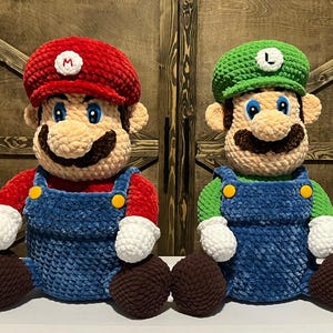 May include: Two plush figures of Mario and Luigi, iconic video game characters. Mario wears a red hat with a white "M", red shirt, blue overalls, and brown shoes. Luigi has a green hat with a white "L", green shirt, blue overalls, and brown shoes.