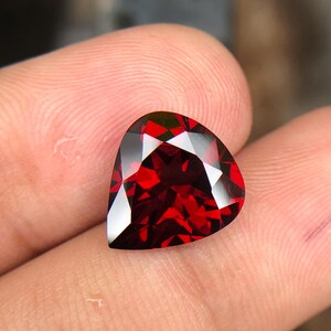 May include: A deep red heart-shaped gemstone with a faceted cut.