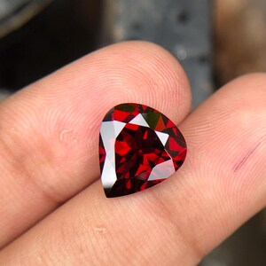 May include: A deep red heart-shaped gemstone with a faceted cut.