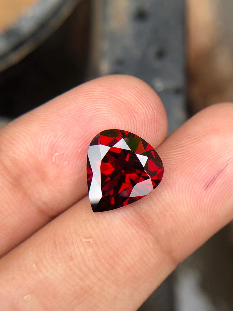 May include: A deep red heart-shaped gemstone with a faceted cut.