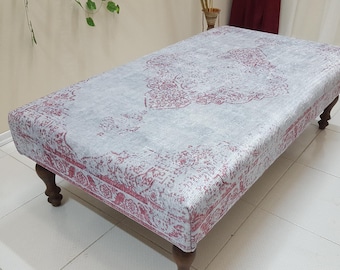 Puede incluir: Un otomano rectangular con una parte superior de tela estampada en gris y rosa y cuatro patas de madera.