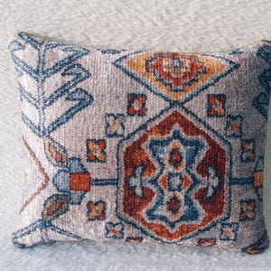 May include: A decorative throw pillow with a beige background and a colourful geometric pattern in shades of blue, red, and orange.