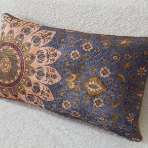 May include: A gray and beige rectangular pillow with a floral pattern. The pattern features a large mandala in the center and smaller floral designs around the edges.