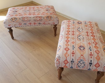 Op de afbeelding: Twee houten voetenbanken met een kleurrijk geometrisch patroon op de stoffen bekleding. De voetenbanken hebben vier poten en staan op een houten vloer.