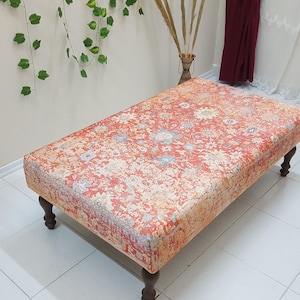 May include: A rectangular ottoman with a red, orange, and cream patterned fabric top and four dark wood legs.