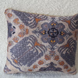 May include: A decorative throw pillow with a beige background and a colourful geometric pattern in shades of orange, blue, and black.