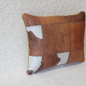 May include: A brown and white patterned cushion with a yellow border. The cushion is made of a soft, textured fabric.