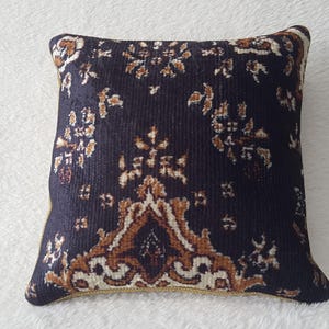 May include: A decorative throw pillow with a dark blue background and a brown and cream floral pattern.