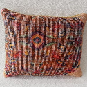 May include: A decorative throw pillow with a colourful floral pattern on a brown background. The pillow is made of a soft, textured fabric.