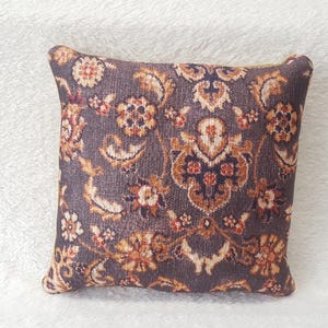 May include: A decorative cushion with a dark grey background and a floral pattern in shades of orange, brown, and white.