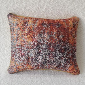 May include: A decorative throw pillow with a rust, orange, and grey abstract pattern.