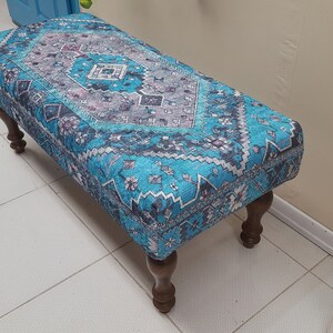 Peut inclure: Un pouf bleu et blanc à motifs avec des pieds en bois. Le pouf a un design traditionnel avec des détails complexes.