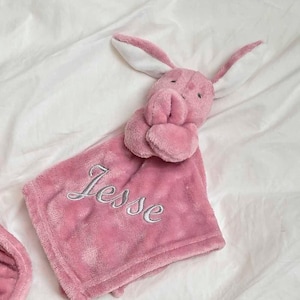 our Babies personalised bunny comforter in Dusky Pink is crafted from super soft plush material, this comforter will keep your baby snug and content. Complete with your babies name personalised/embroidered to the front.