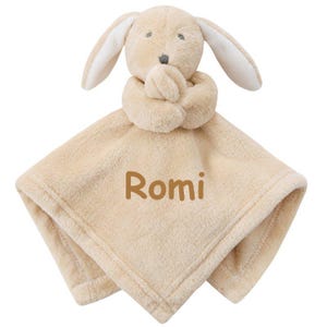 May include: A beige plush bunny security blanket with the name "Romi" embroidered on it.
