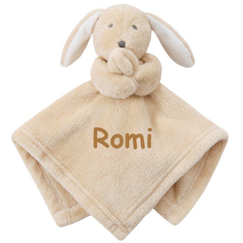 May include: A beige plush bunny security blanket with the name "Romi" embroidered on it.