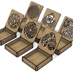 Könnte beinhalten: Eine Sammlung von sieben Holzboxen mit Scharnierdeckeln. Jeder Deckel weist ein einzigartiges lasergeschnittenes Design auf, darunter geometrische Muster, Blumenmotive und abstrakte Formen. Die Boxen sind aus hellem Holz gefertigt und offen, wodurch ihre leeren Innenräume sichtbar werden.