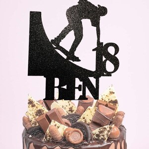 May include: Black glitter cake topper featuring a silhouette of a person skateboarding on a ramp with the number 18 and the name "BEN" underneath.