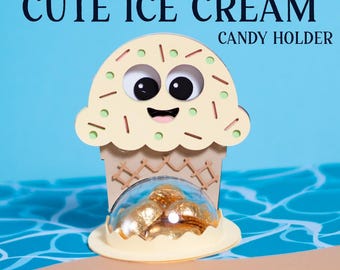 May include: A cute ice cream cone shaped candy holder with a smiling face and sprinkles. The holder is made of wood and has a clear plastic dome to hold the candy. The holder is sitting on a beach scene with blue water and sand.
