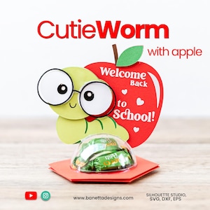 May include: A whimsical school-themed gift featuring a cartoon worm character wearing glasses, paired with a red apple that says "Welcome Back to School!". The design includes a clear dome with wrapped candies, all set on a red hexagonal base.
