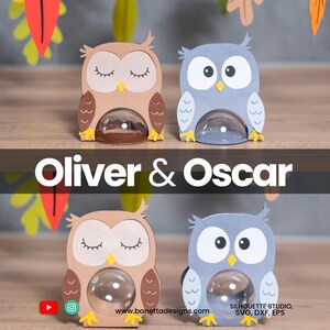May include: Two owl-shaped containers, one tan and one blue, with clear, rounded bellies. The tan owl has closed eyes, while the blue owl has open eyes. The text "Oliver & Oscar" is displayed. The website address is www.banettadesigns.com.