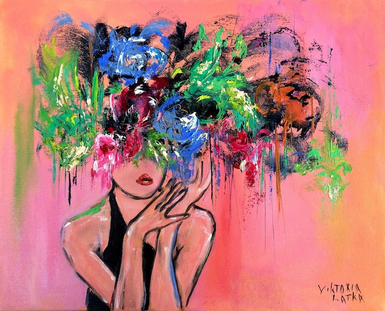 May include: An original acrylic painting on canvas. The artwork depicts a woman with a floral headdress in shades of blue, red, green, and orange. The background is a soft pink, and the woman is wearing a black top. The artist's signature is in the bottom right corner.