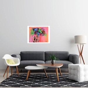 May include: An abstract art print featuring a woman with a floral headpiece. The artwork has a pink and orange background with a white border. The woman's face is partially visible, with red lips. The floral headpiece is a mix of blue, green, and purple.