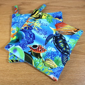 May include: Two blue and green pot holders with a colorful underwater scene featuring fish, coral, and a sea turtle.