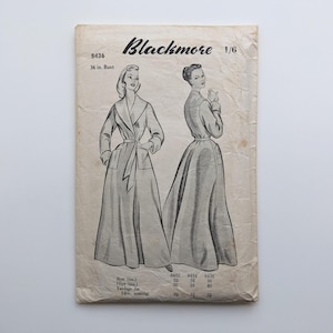 May include: Vintage "Blackmore" sewing pattern showing illustrations of a long coat with a belt. The pattern includes a 36-inch bust size. The cover is aged with visible wear and tear.