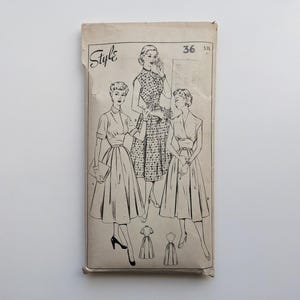 Puede incluir: Patrón de costura vintage titulado "Style" con ilustraciones de tres vestidos. El sobre beige presenta dibujos lineales negros de mujeres con los vestidos. El número "36" es visible en la esquina superior derecha.