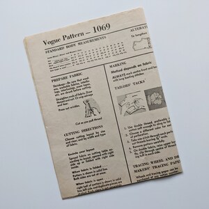 Puede incluir: Un patr&oacute;n de costura Vogue vintage, titulado "1069", con medidas corporales est&aacute;ndar e instrucciones. El papel blanquecino presenta texto e ilustraciones que detallan la preparaci&oacute;n de la tela, las instrucciones de corte y las t&eacute;cnicas de sastrer&iacute;a. El patr&oacute;n est&aacute; desgastado.