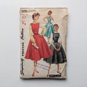 May include: Vintage Simplicity sewing pattern envelope with illustrations of dresses. The main dress is red with a yellow blouse, and the other dresses are blue and black. The envelope is aged and has the number 1270.