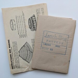 May include: A vintage Leach-Way dress pattern, with sewing instructions and illustrations. The pattern is in a tan paper envelope, marked "Leach-Way PATTERN 14264 DRESS BUST 32". The instructions are printed on aged paper.